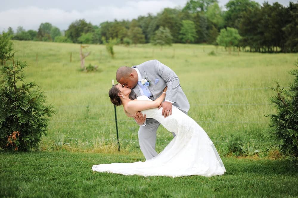 bride and groom kissing in the field