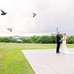 pigeons flying over bride and groom
