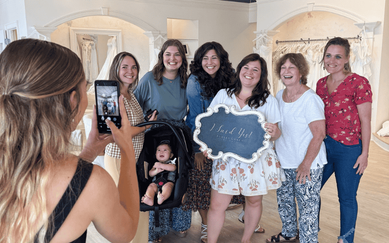 A Group taking a picture with the bride holding a sign saying "i SAID YES TO THE DRESS"