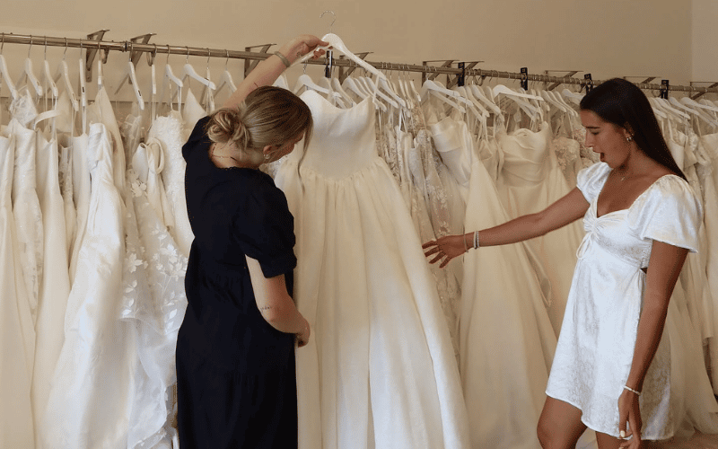stylist and bride looking for wedding dress in the rack