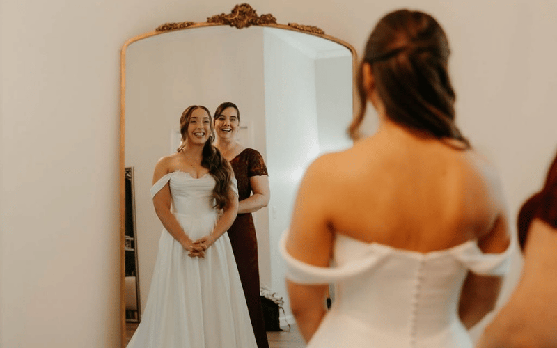 wedding dress details, stylist and bride in front of mirror